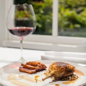 A glass of pinot noir next to a plate of food.