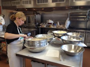 Woman with an apron cooking with big bowls.