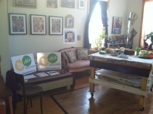 A photo of the art studio. There's a desk, couch, and some art lying around.