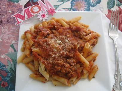 Pasta on a plate with the sauce on top.