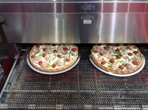 Two pizzas coming out of the oven.