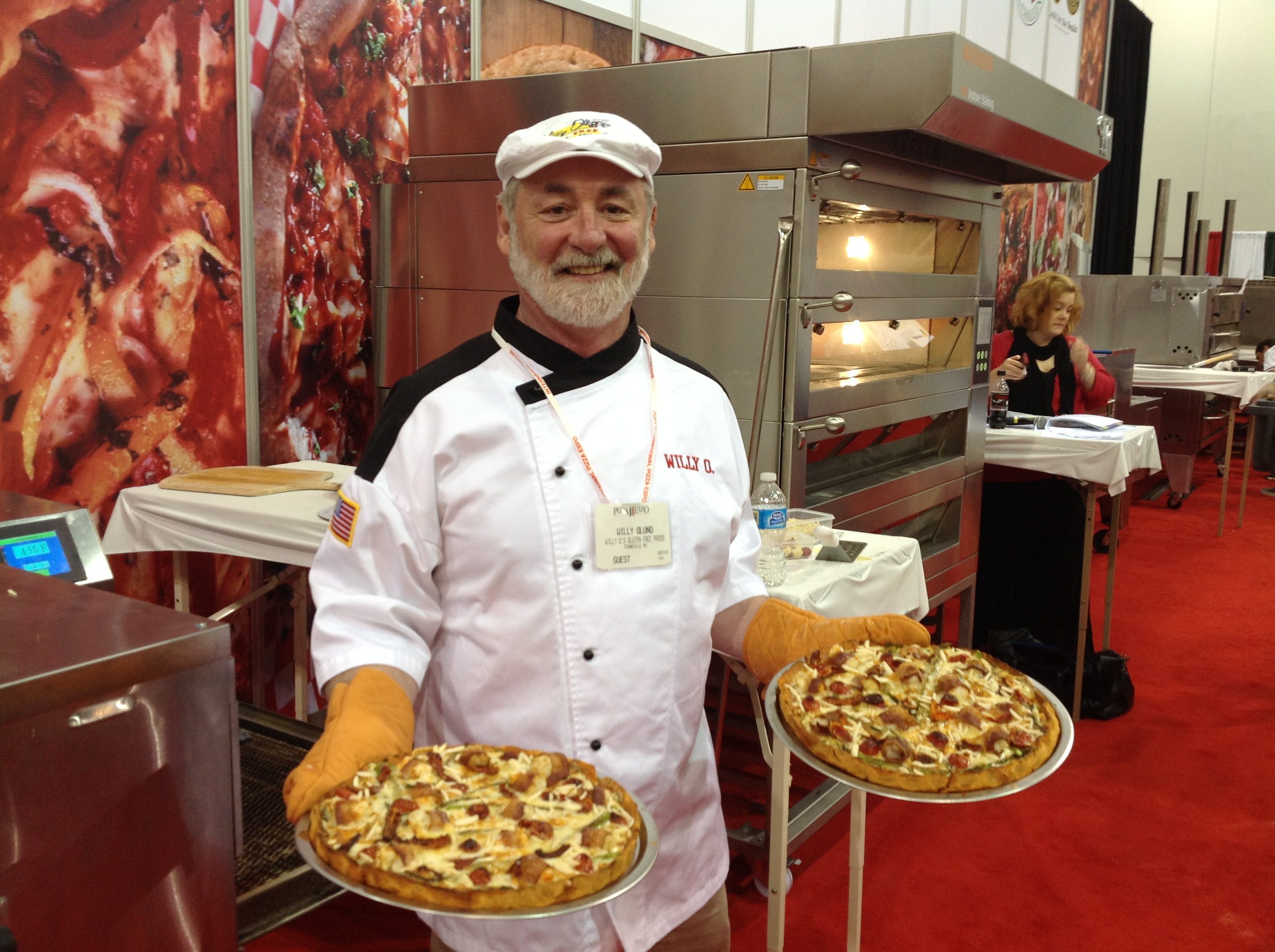 Willy O smiling and holding two pizzas.