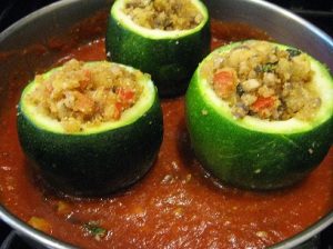 The stuffed zucchinis are sitting in a pot of sauce.