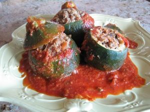 The finished product: stuffed zucchinis on a plate, covered in sauce.