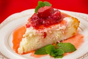 A slice of cheesecake with a strawberry on top.
