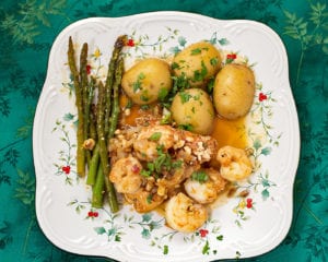 A plate of salmon, shrimp, potatoes, and asparagus. 