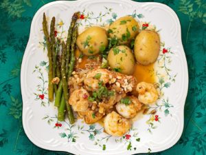 A plate of salmon, shrimp, potatoes, and asparagus.