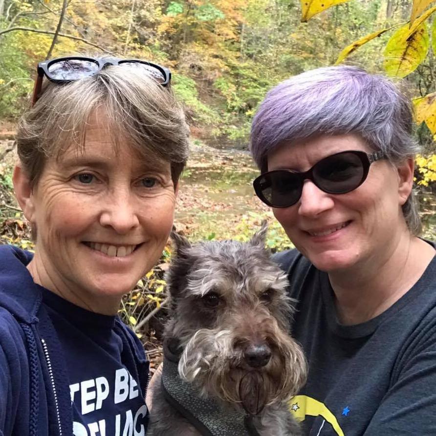 A portrait of Claire, her spouse Jenn, and their dog.