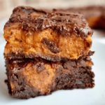 Two black and orange brownies are stacked on top of each other.
