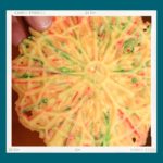 A circular, red and green streaked cookie against a teal background.