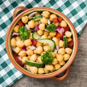 A bowl of chickpeas mixed with peppers, onions and cucumbers. 