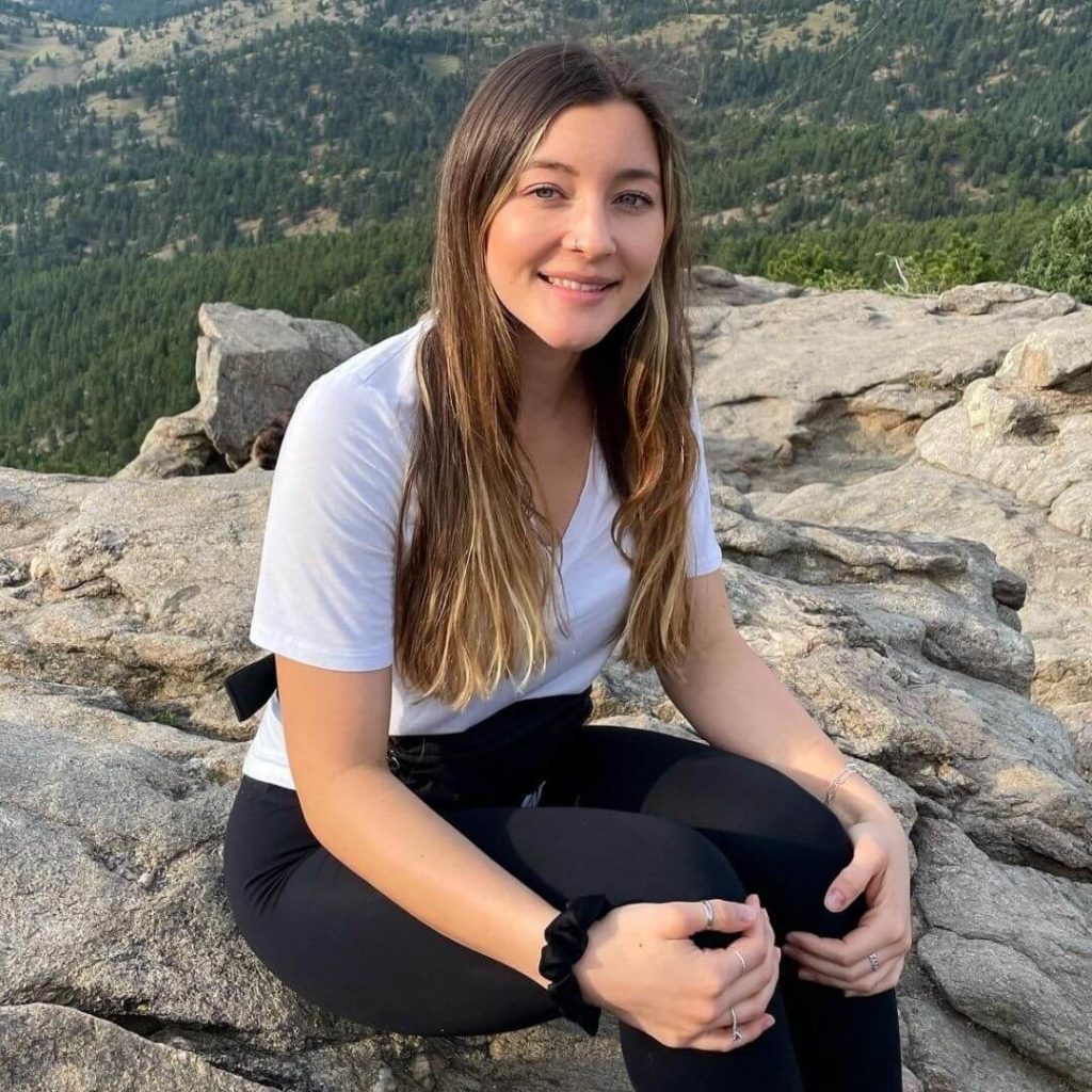 A photo of Kristina sitting on a rock outside.