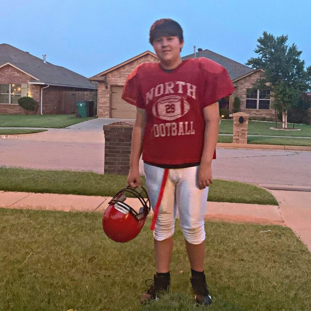 Hayden standing outside in his football uniform.