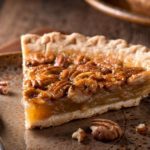 A slice of pecan pie on a plate with a fork.