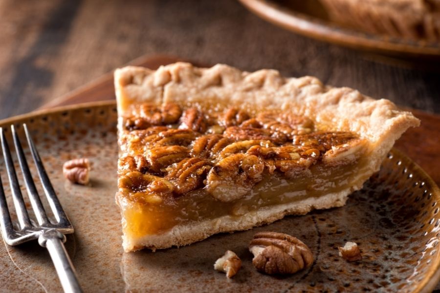 A slice of pecan pie on a plate with a fork.