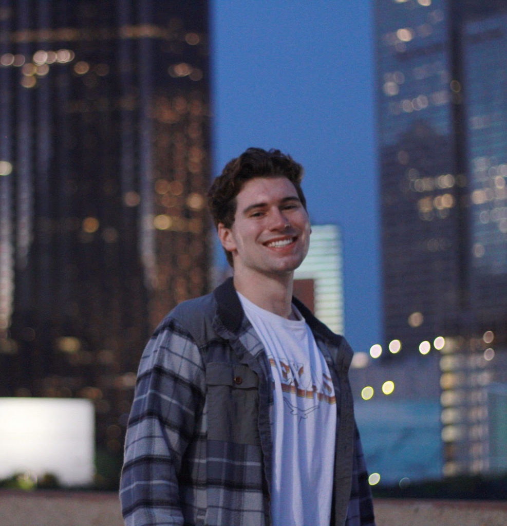 A photo of Jake Woods. It's evening and skyscrapers are visible behind him.