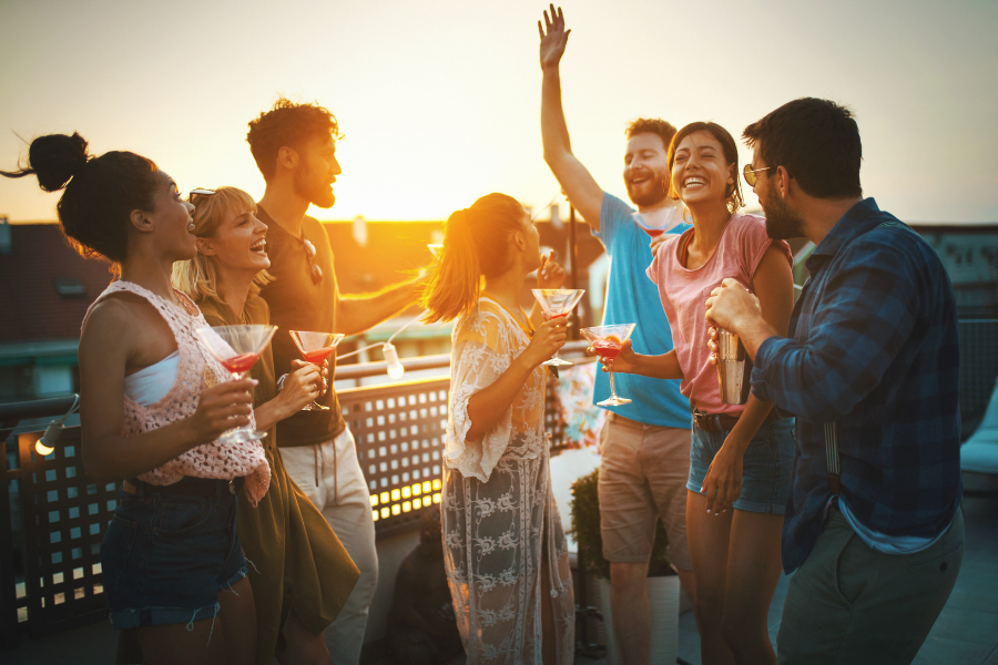 A group of people smiling outside and holding glasses. 