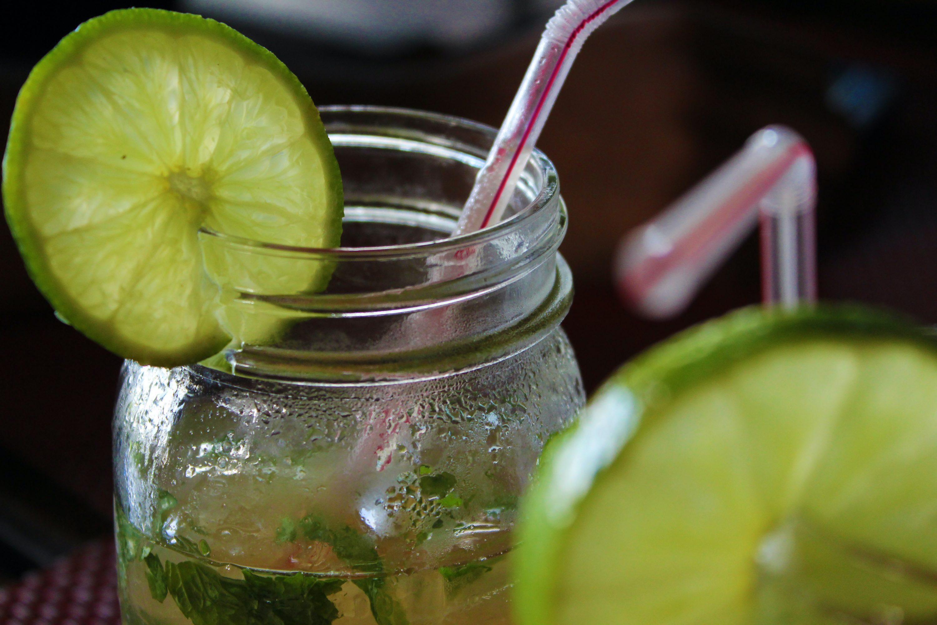 A photo of two glasses filled with a drink. A lime slide is wedged onto the rim. 