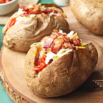 Two BLT ranch baked potatoes on a plate ready to eat.