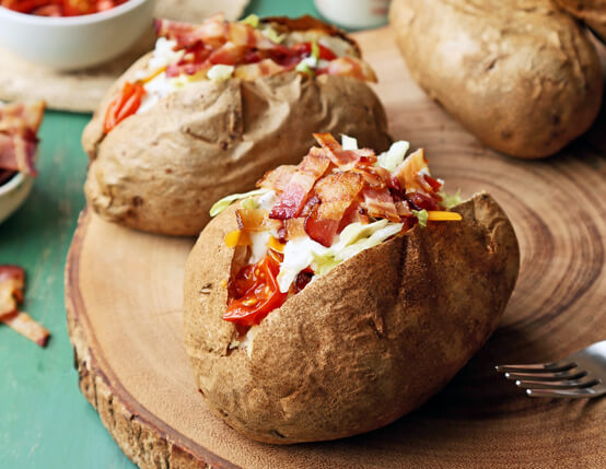 Two BLT ranch baked potatoes ready to eat.