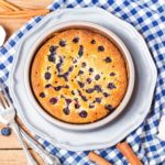 A pan of blueberry lemon cake on a blue plaid tablecloth.