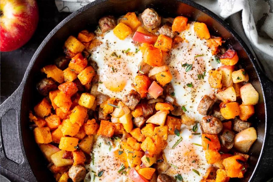 The butternut hash in a cast iron skillet. An apple is visible in the top left corner.