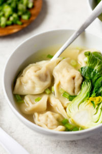 A bowl of wonton soup with baby bok choy.