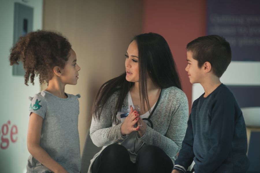 A school nurse talking to two kids. 