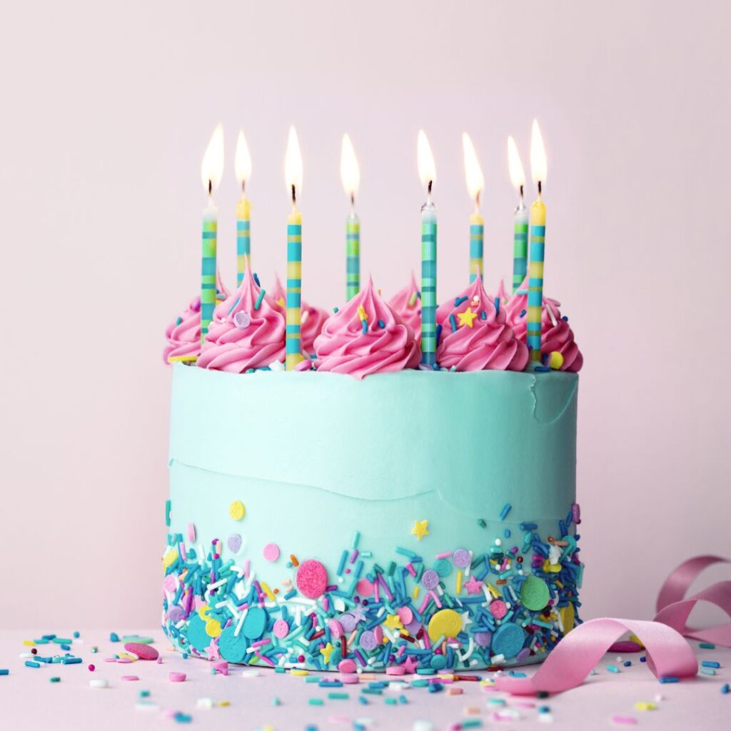 A photo of a brightly colored cake with the candles lit.