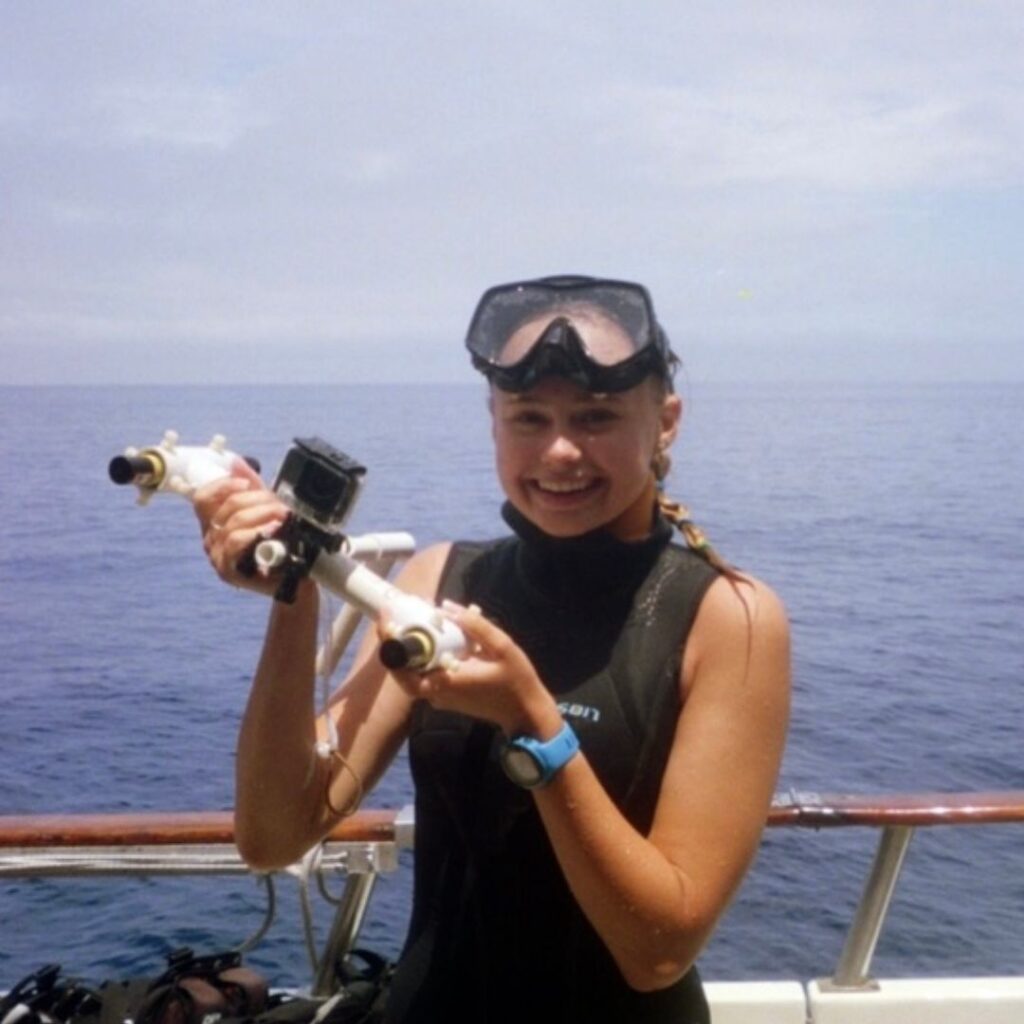 A photo of Mariah smiling on a boat. She has snorkeling gear on.