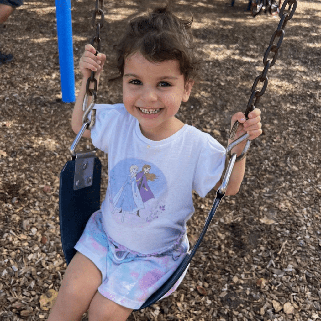 A photo of Kamila on a swing, smiling.