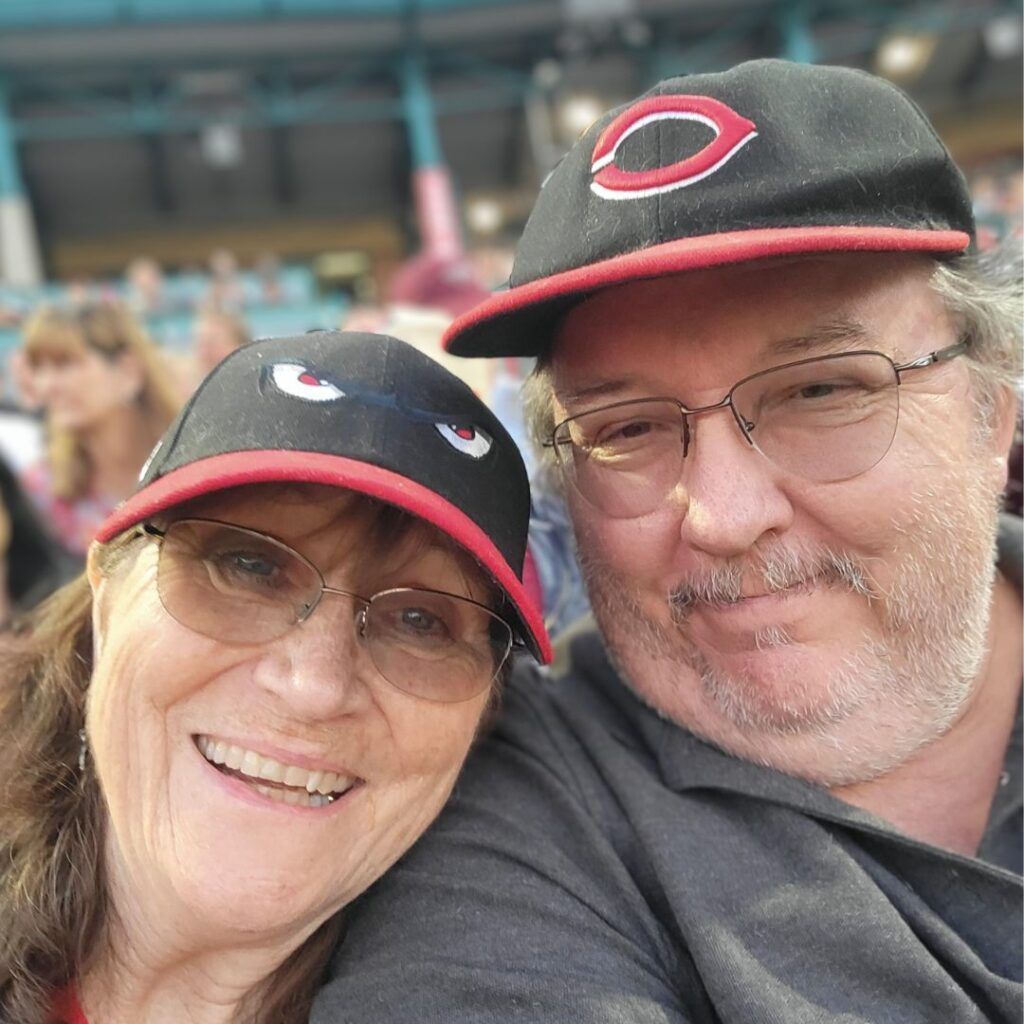 A photo of Maureen and her husband smiling at a sports event.