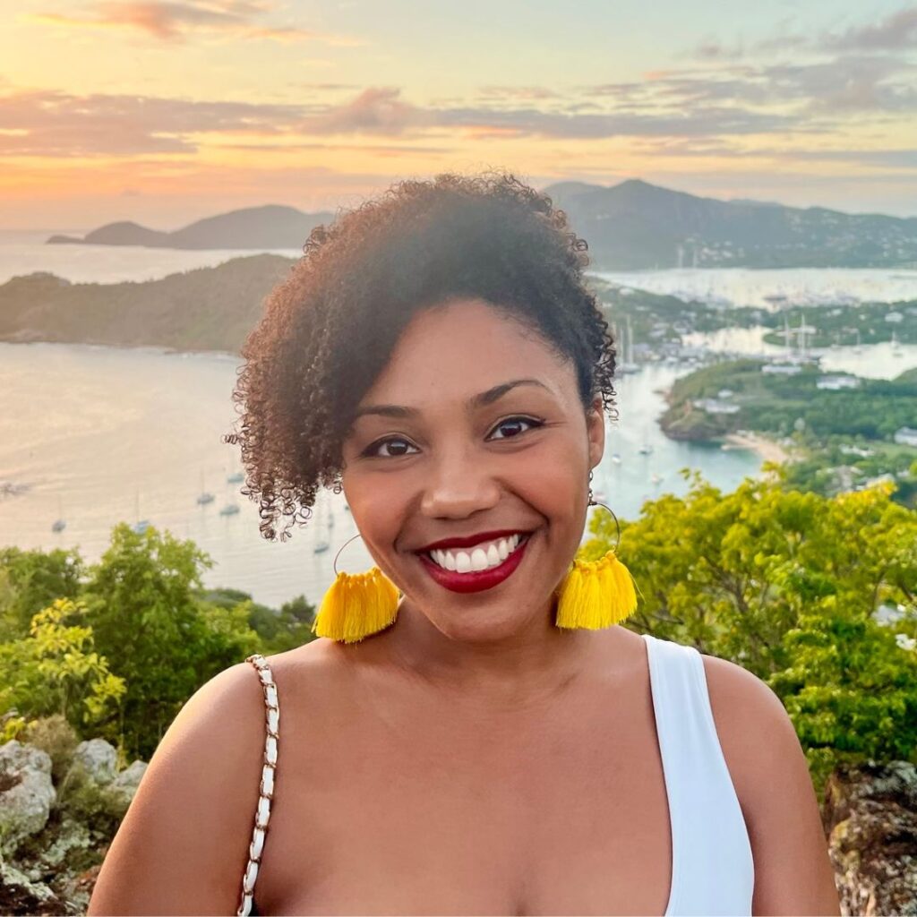 A photo of Bionqua smiling outside in front of a sunset