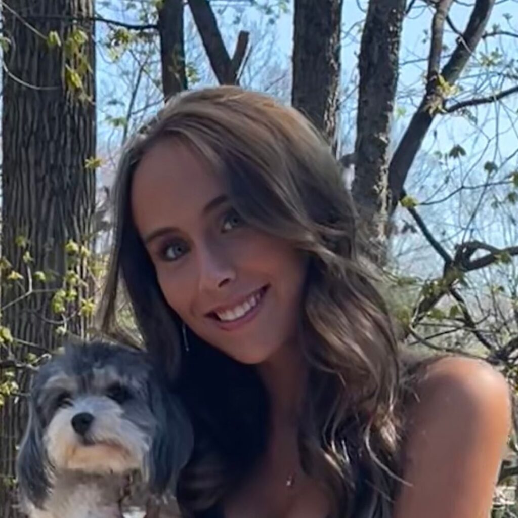 A photo of Brooke smiling. She's also holding a small dog.