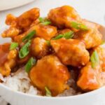 A bowl of orange chicken and rice.