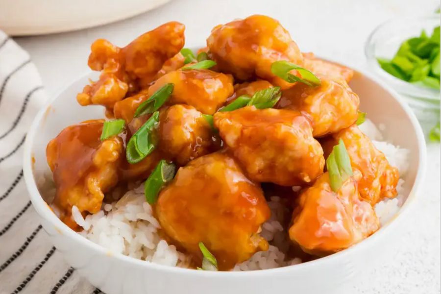 A bowl of orange chicken and rice. 