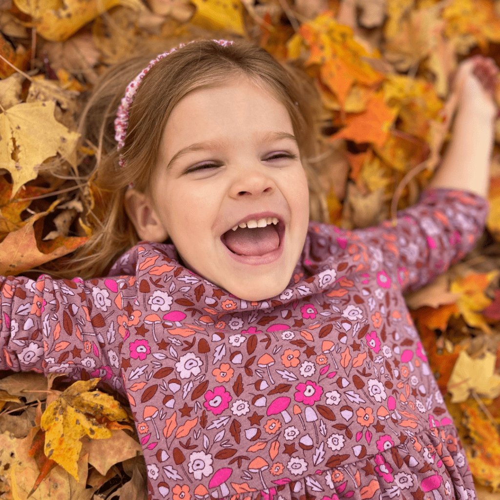 Mia lays on her back in autumn leaves.