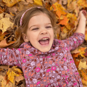 Mia lays on her back in autumn leaves.