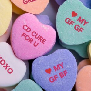 A pile of candy hearts, read things like "CD cure for U," "❤️ my GF GF," "❤️ my GF BF," "XOXO"