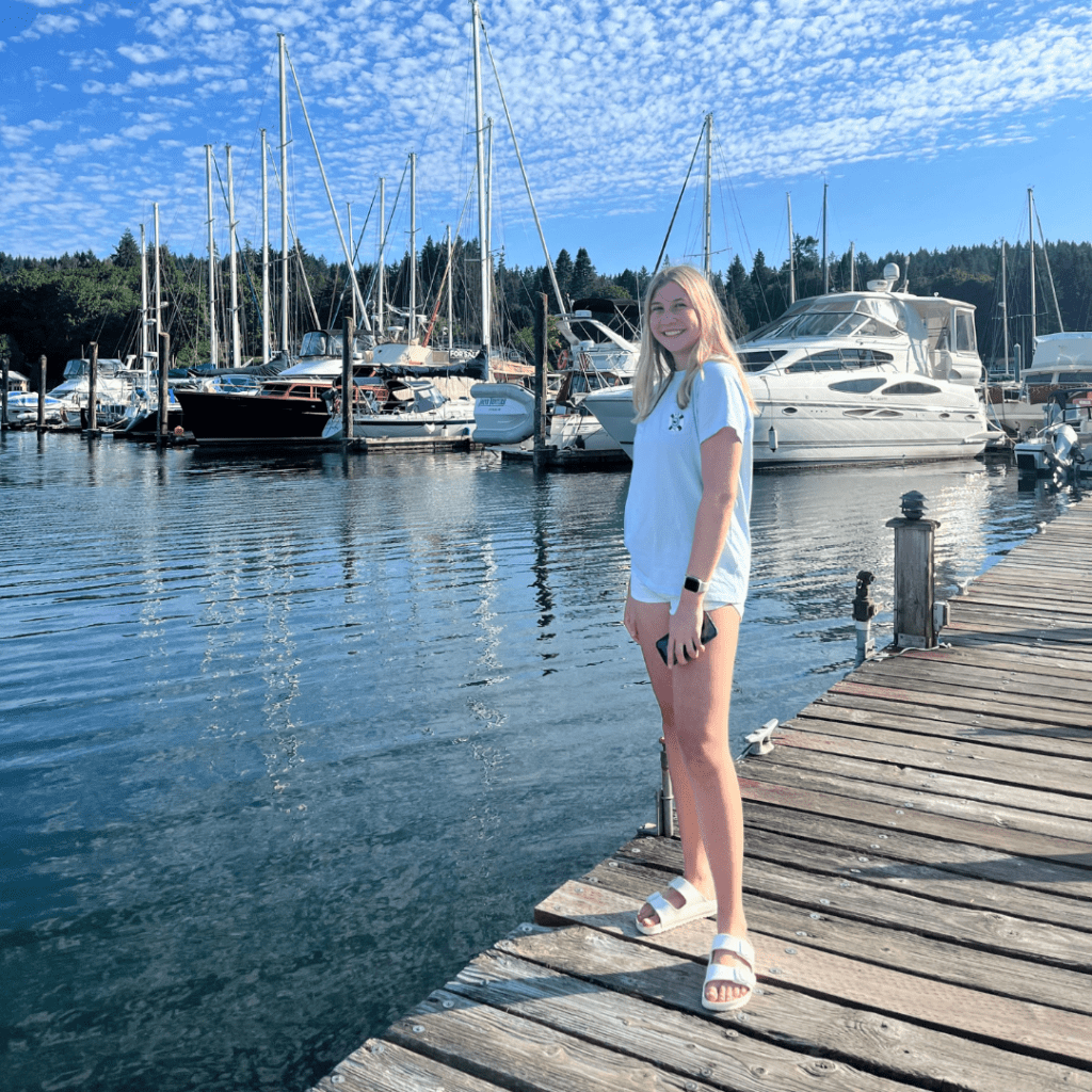 Claire stands on a dock in front of boats and water