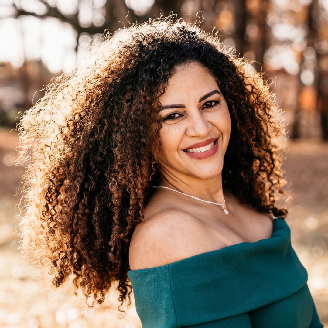 A photo of Elimarie smiling. She has long, curly hair. 