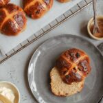 A photo of hot cross buns. There are also bowls of various ingredients.