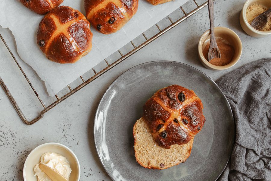 A photo of hot cross buns. There are also bowls of various ingredients.