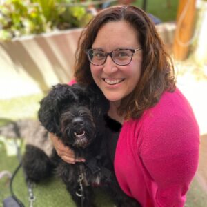 Kendra and her gluten detection service dog Suki sit in front of a fence