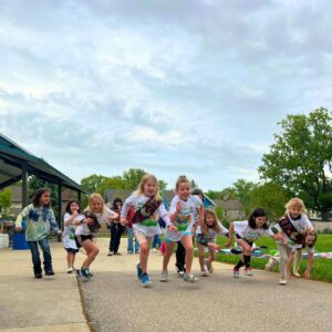 A troop of girl scouts in Step Beyond Celiac 5K shirts running.