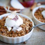 A bowl of apple crumble with a scoop of ice cream on top.