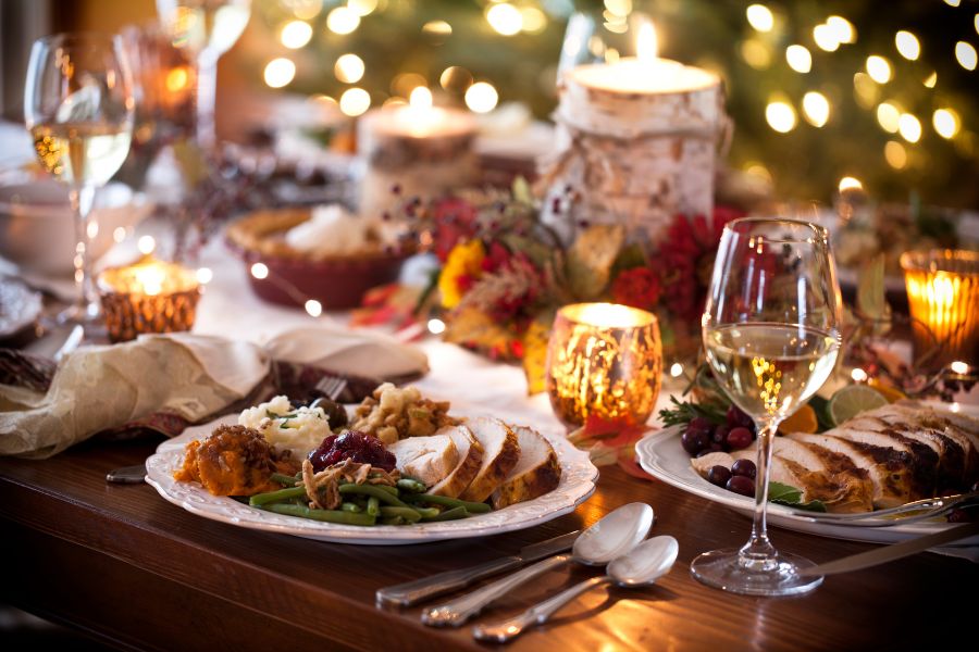 A plate filled with Thanksgiving food on a table with various autumnal decor and dishes. 