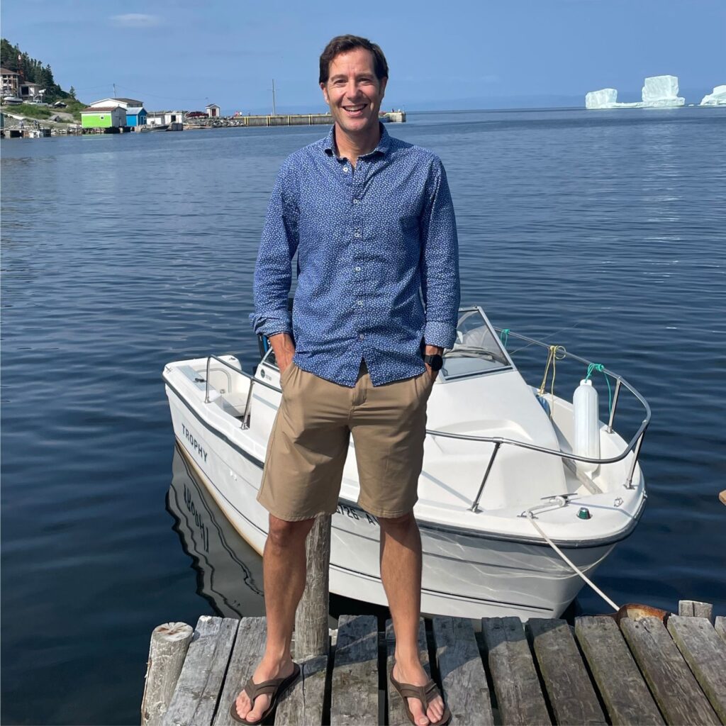 A photo of Marty smiling. He's on a doc in front of a boat.