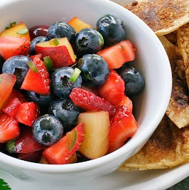 A bowl of fruit salsa next to a plate of cinnamon chips.