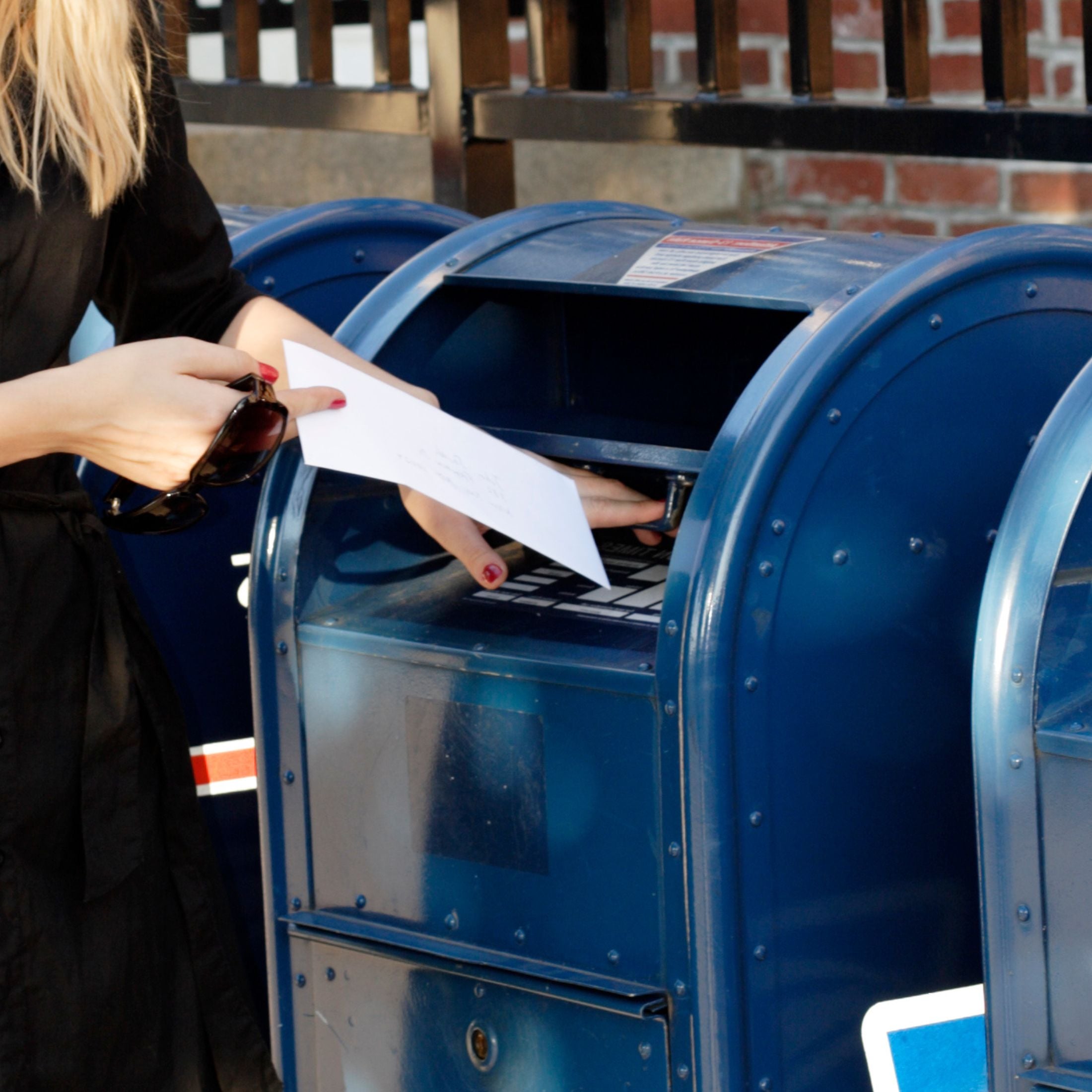 Person slipping a letter into a post box.